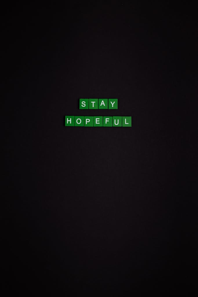 Black background with green Scrabble tiles spelling 'Stay Hopeful' for a minimalist, motivational scene.