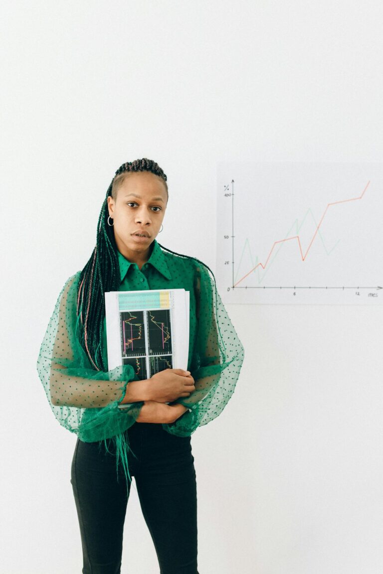 Young businesswoman in green blouse holding financial charts, standing against a growth graph